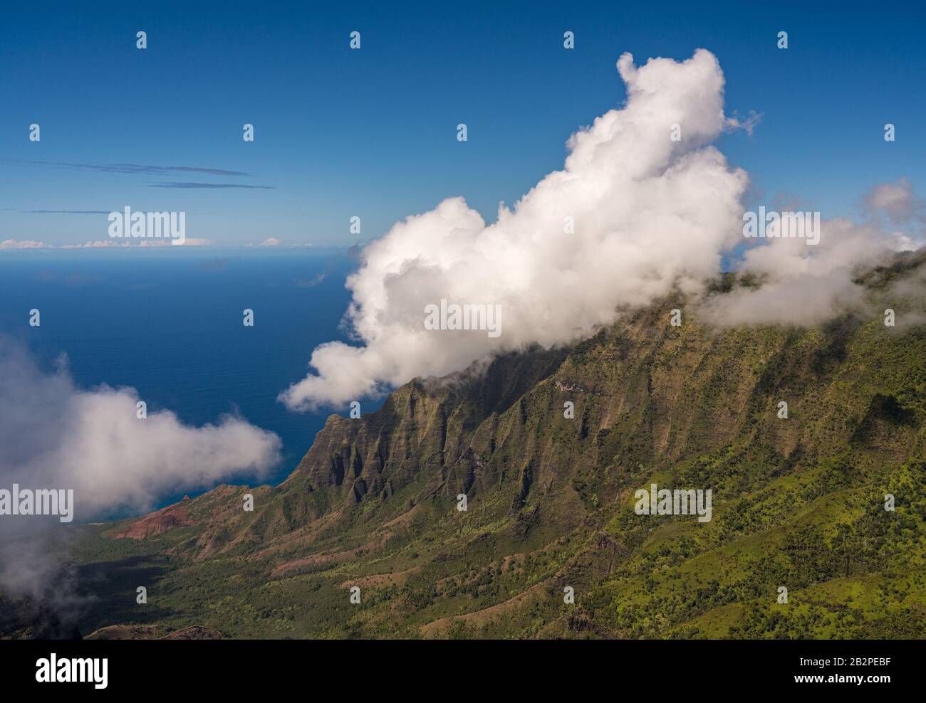 Fluted rocks of the Na Pali mountains with clouds forming over the peaks from Kalalau lookout on Kauai Stock Photo