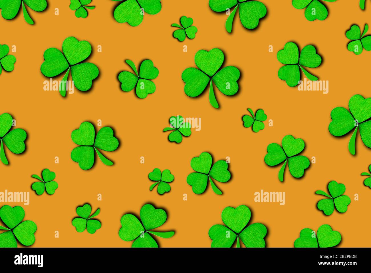Pattern of green clovers or shamrocks isolated on orange background. St. Patrick's Day Holiday concept. Spring background. Stock Photo