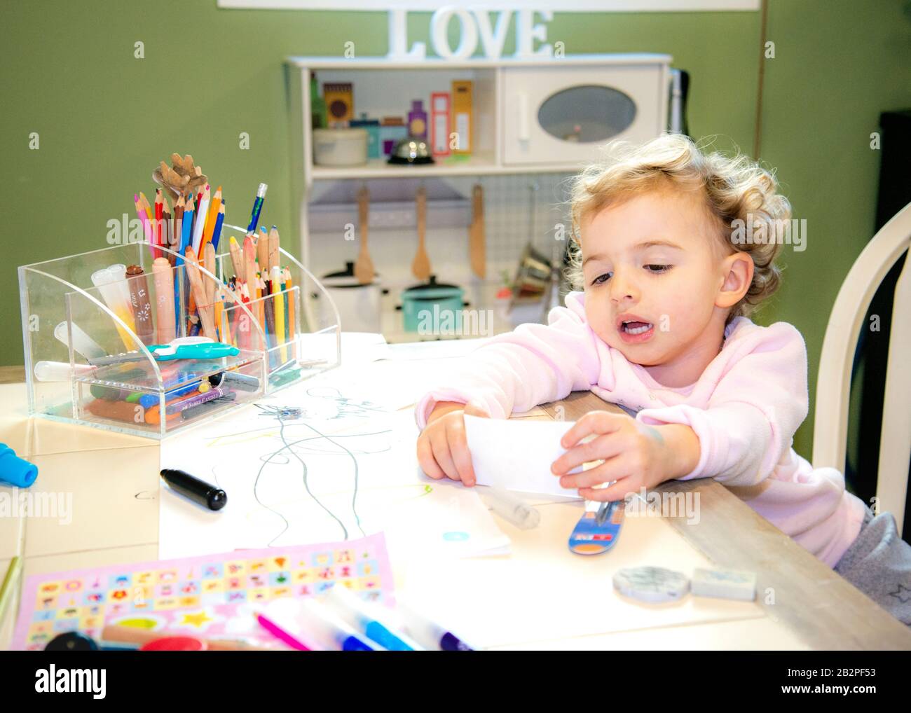 child sitting at table having fun,making her own arts and crafts at home. Stock Photo