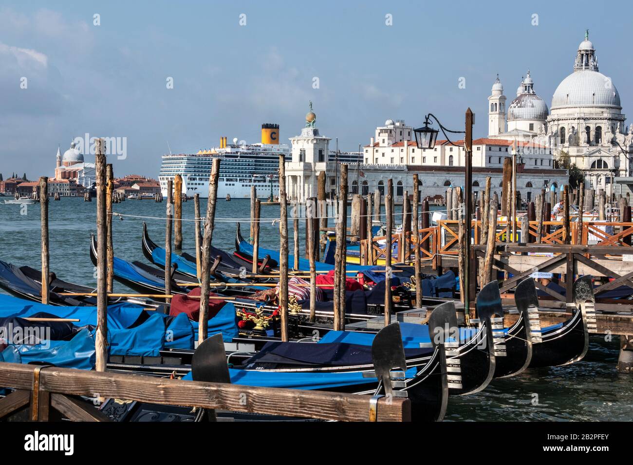 Daily arrival of the early morning cruise ships into St Mark's Square, with gondola's in foreground, Venice, Italy Stock Photo