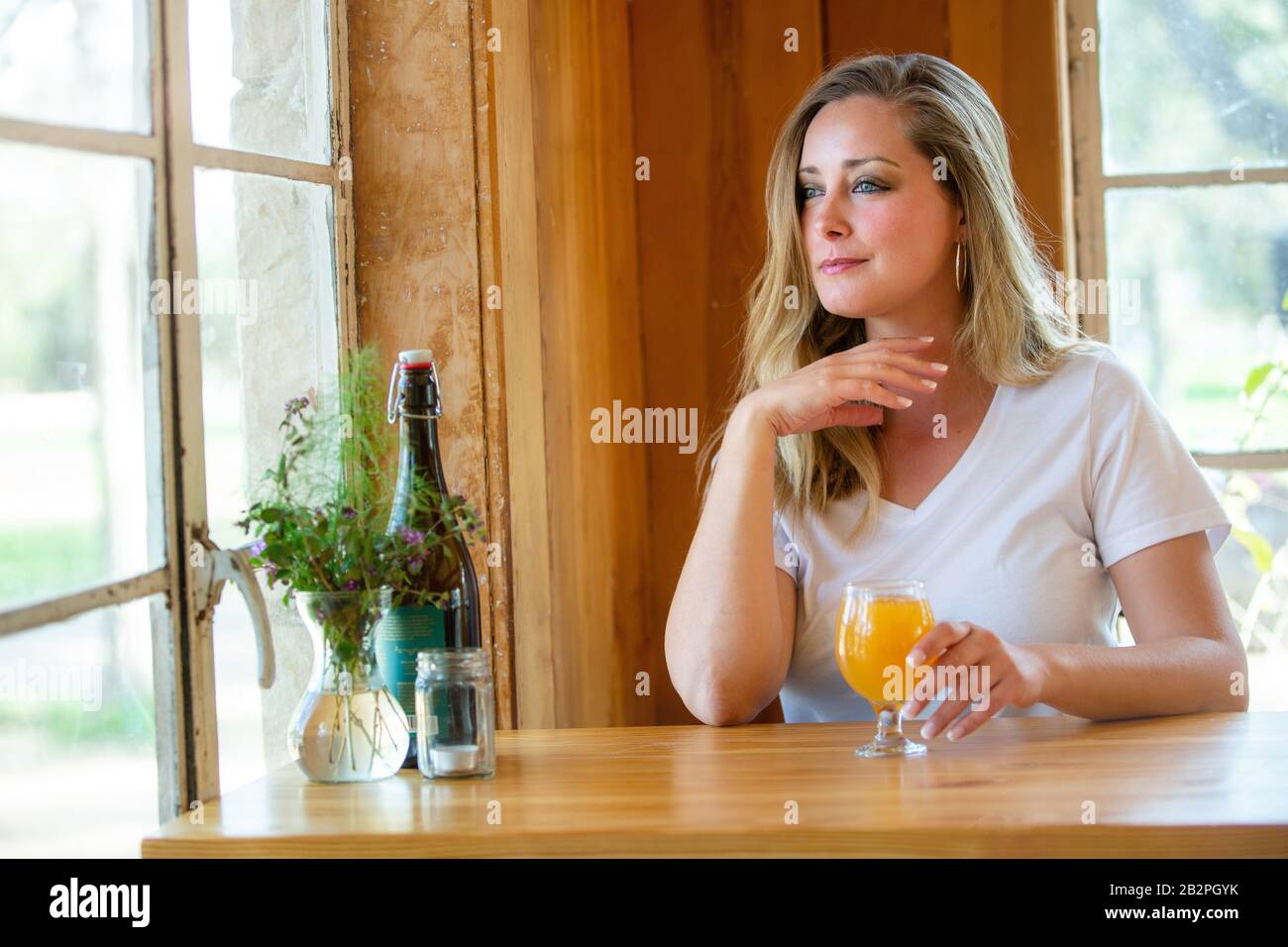 A woman enjoying a delicious IPA wheat NEIPA craft beer pint in a tulip glass at a bar, pub, restaurant, during weekend Stock Photo
