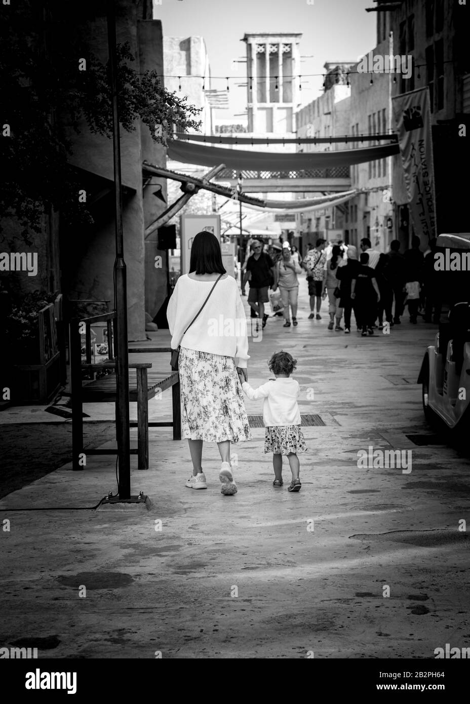 Black and white back shot of mother and small child walking through market at Dubai Creek UAE. Stock Photo