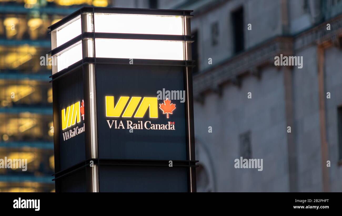 VIA Rail Canada logo atop of a sign out-front of Toronto Union Station lit at night. Stock Photo