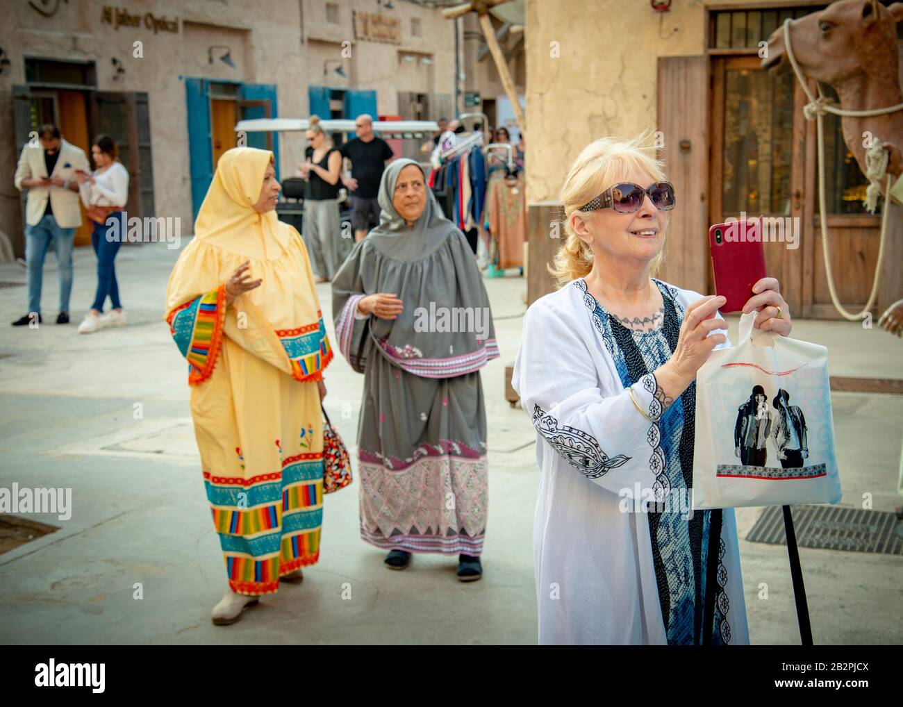 Middle aged lady/tourist taking photos on iphone at old town market in Dubai UAE Stock Photo