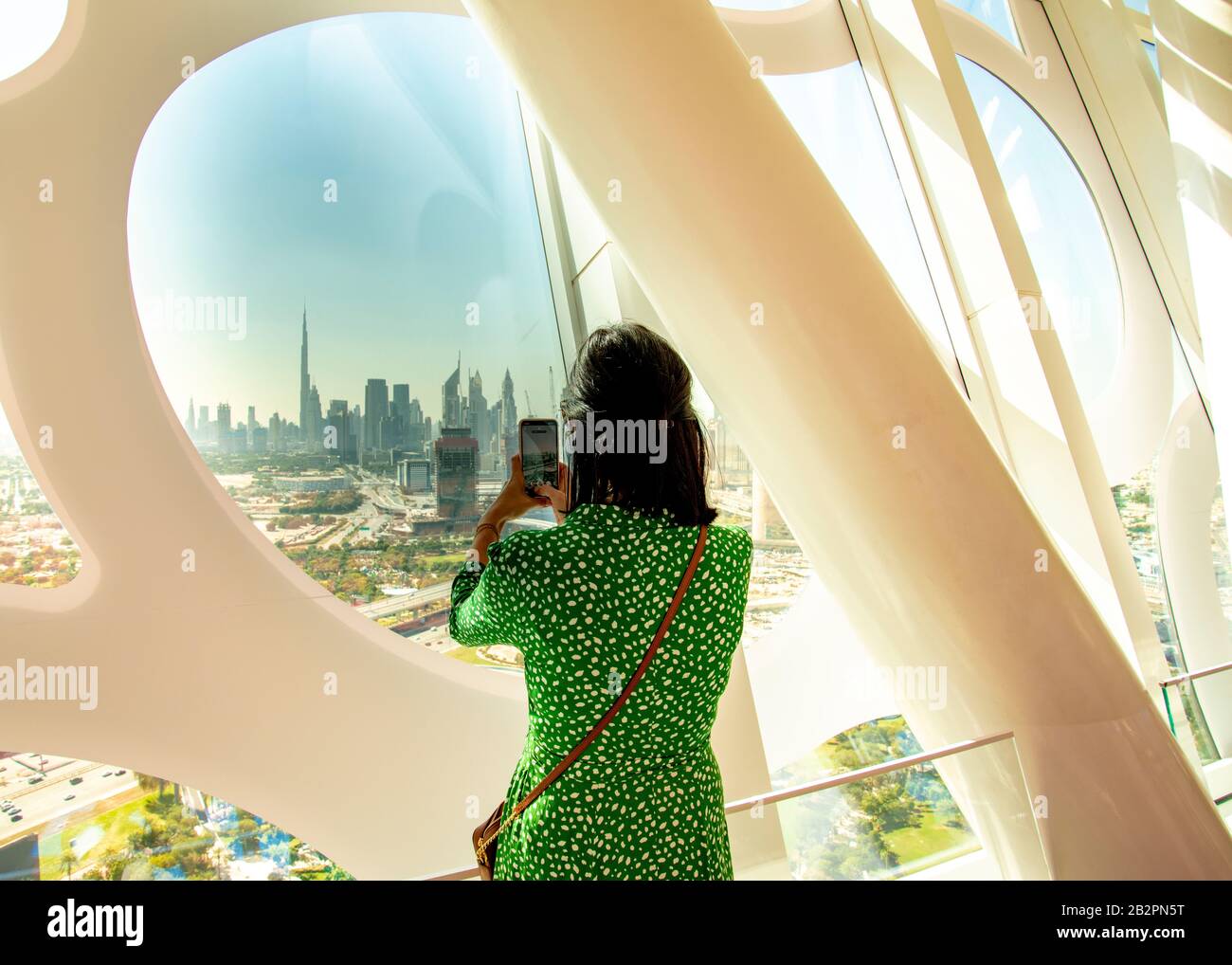 Woman taking photographs of city landscape using mobile phone from Dubai Frame UAE Stock Photo