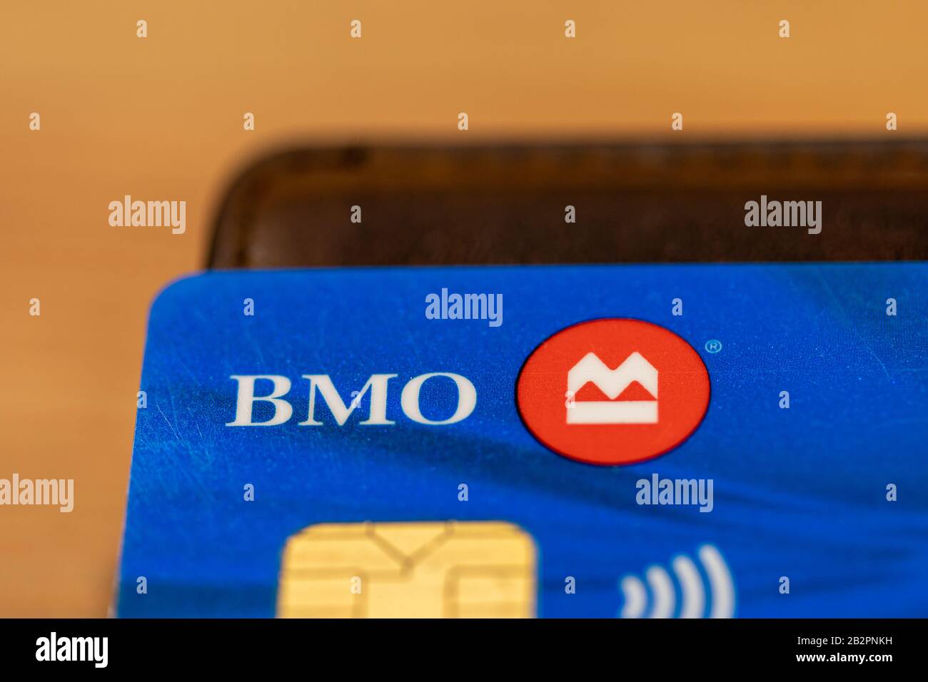 BMO (Bank of Montreal) logo on a blue debit card, atop of a wallet on a desk. Stock Photo