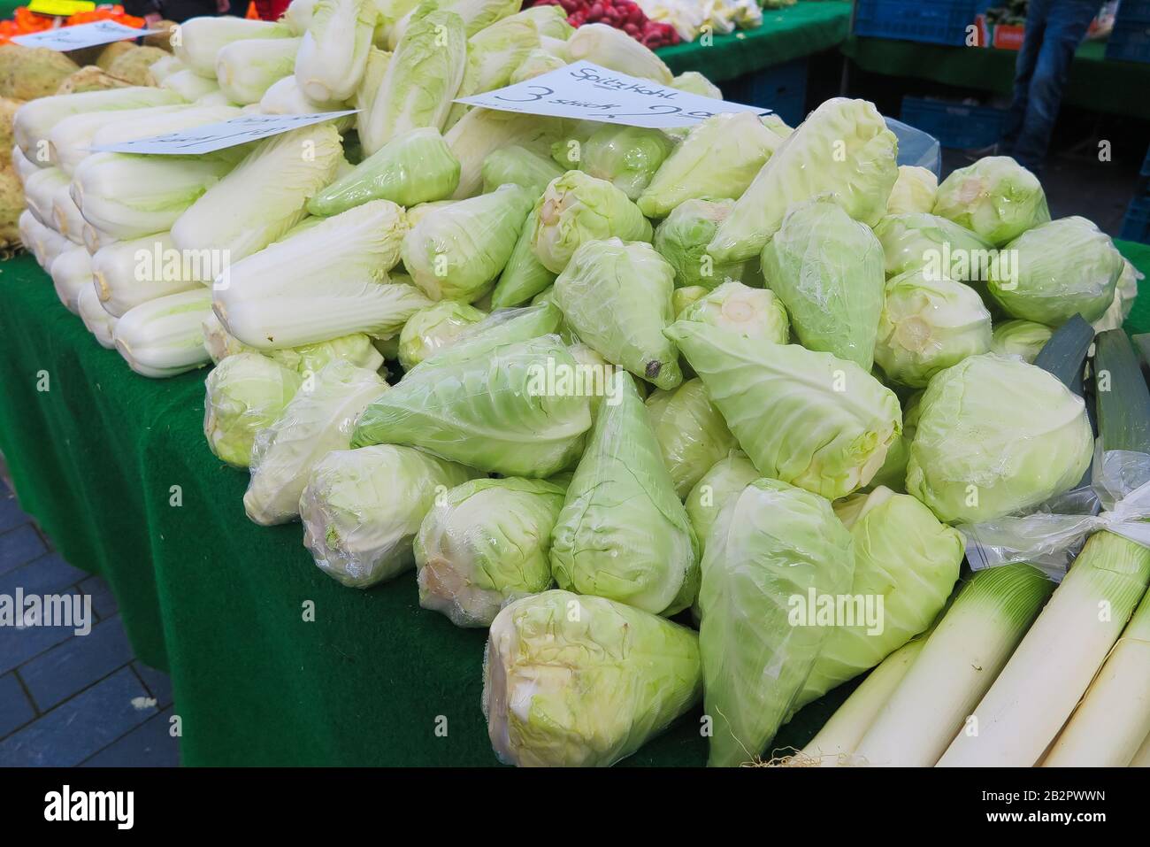 Pile of green pointed head cabbages (german Word on sign Spitzkohl) on