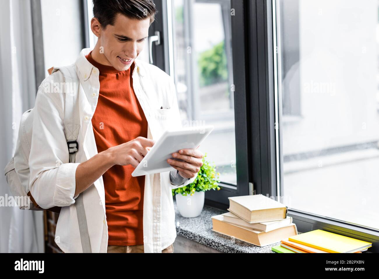 handsome student smiling and using digital tablet in apartment Stock Photo