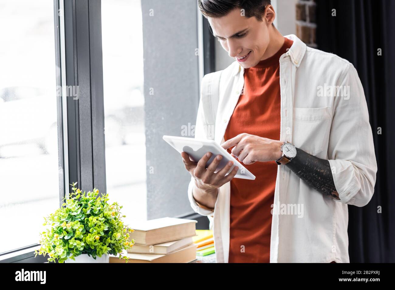 handsome student in shirt using digital tablet in apartment Stock Photo