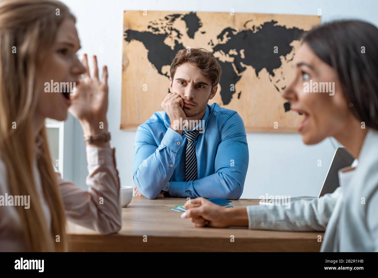 selective focus of quarreling couple near bored travel agent Stock Photo