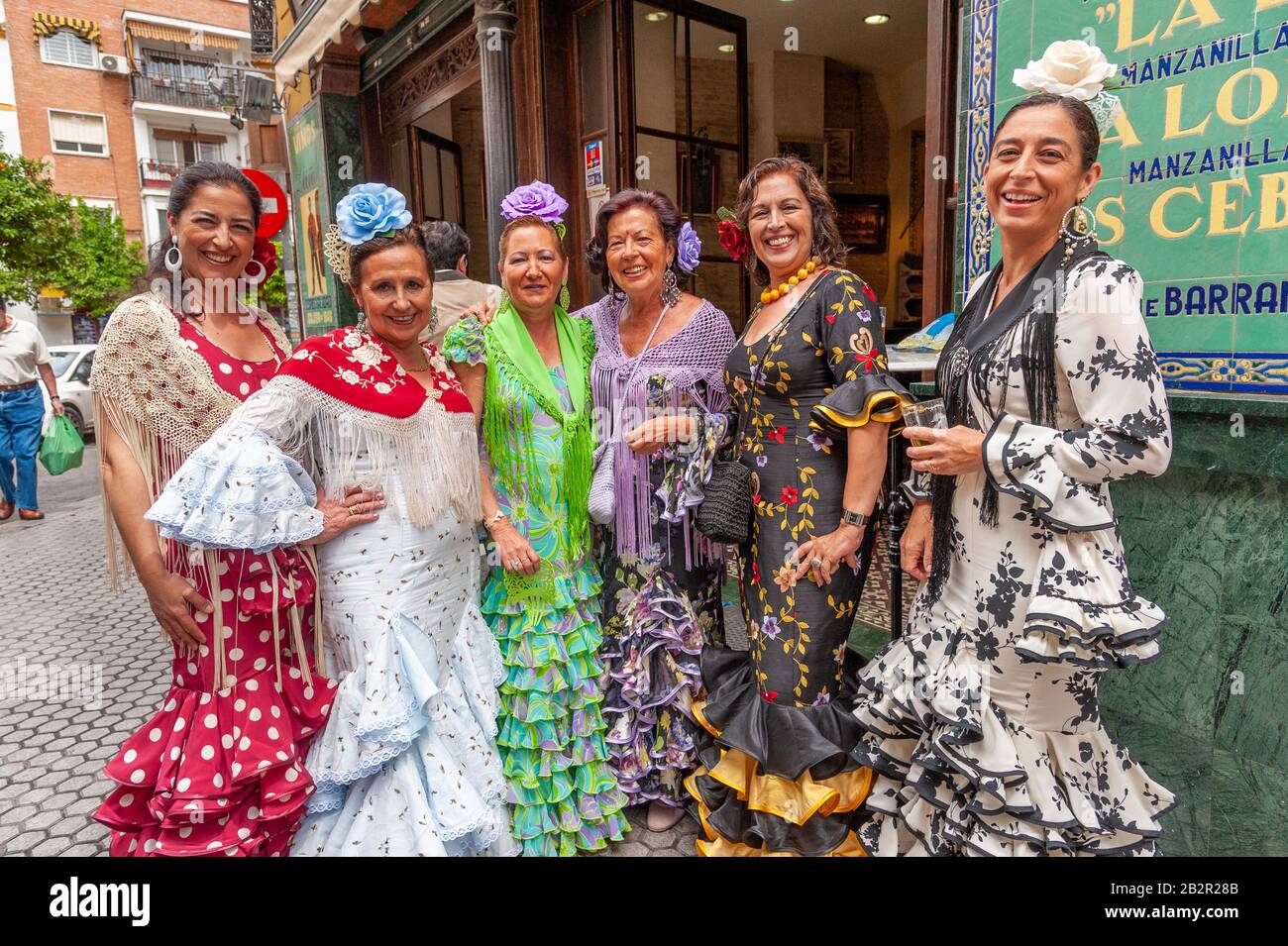 Group of women wearing colourful flamenco dresses outside a bar during the Seville April Fair, Spain Stock Photo