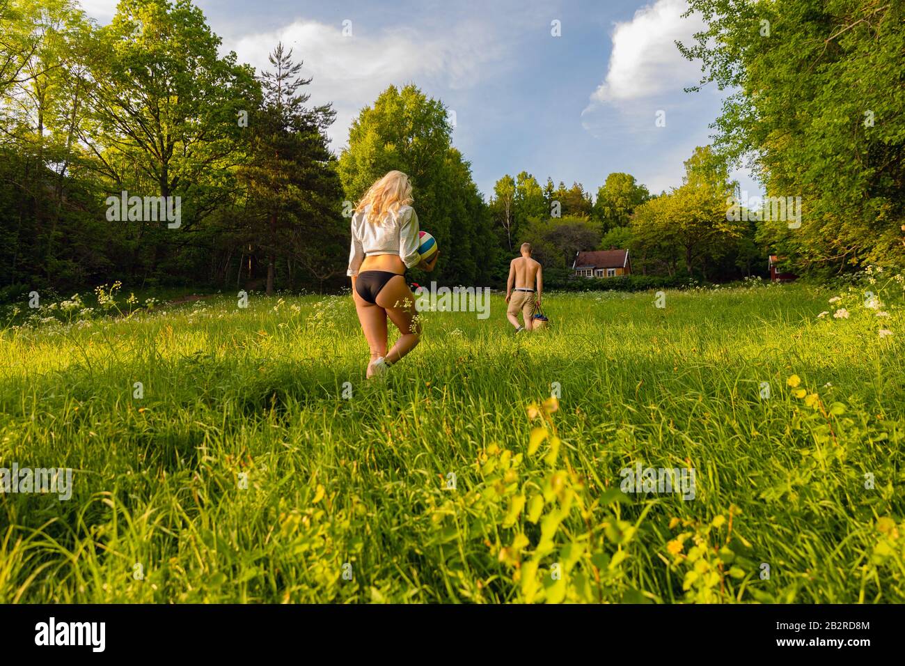 Young Couple Walking On Grass In Idyllic Forest Stock Photo