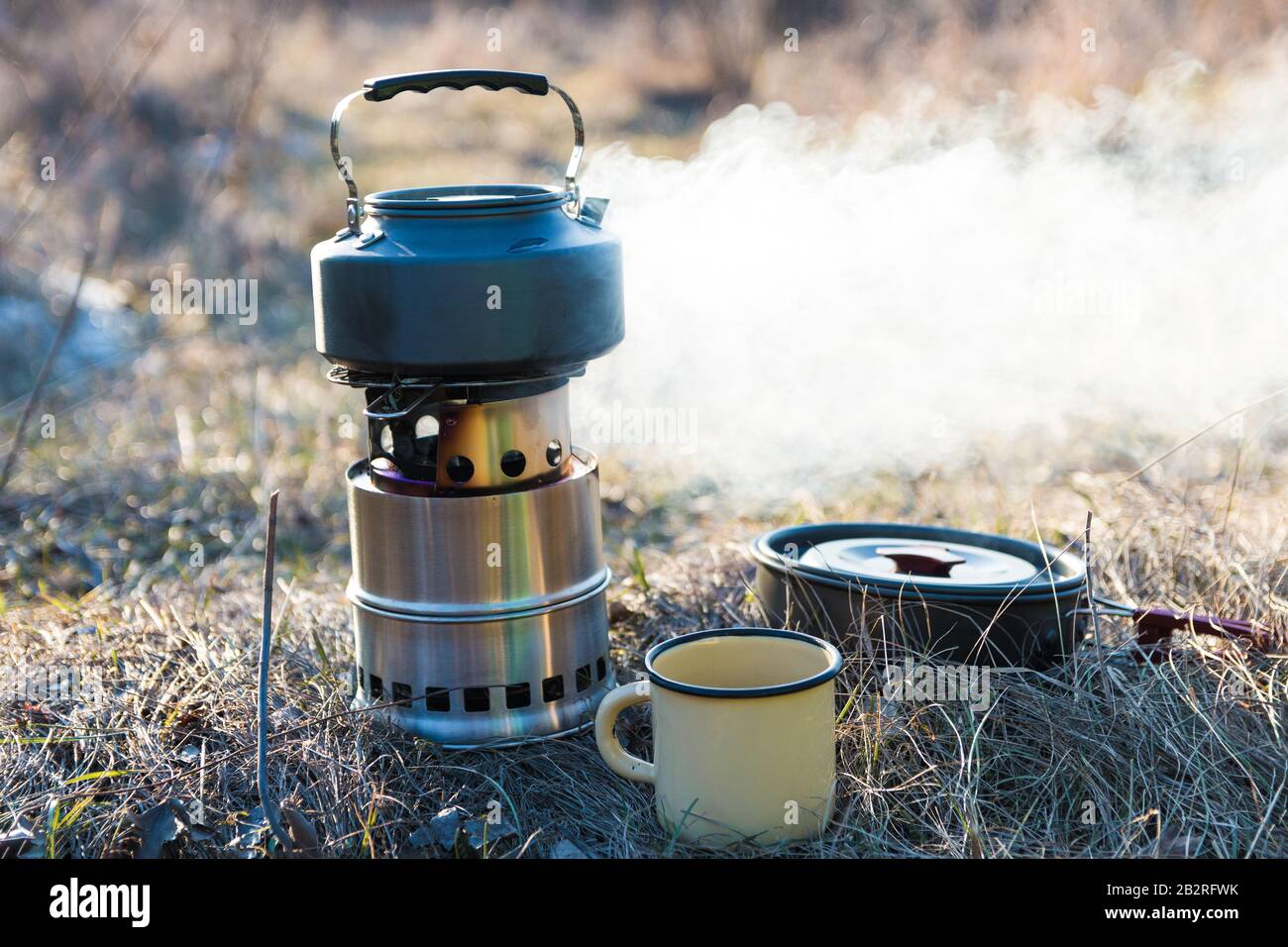 kettle on fire burner. outdoor camping cooking on solid wood burner