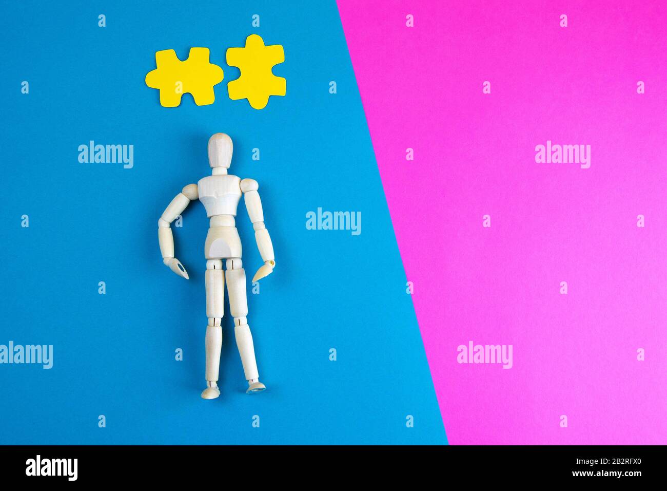 Wooden figurine of a man with yellow puzzles over his head on a blue ...
