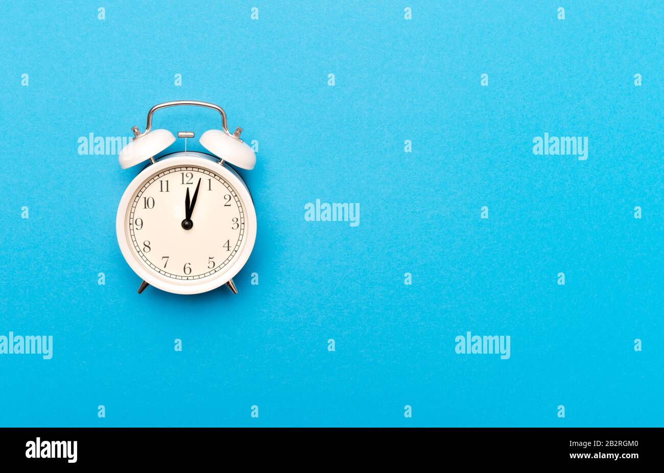White vintage alarm clock on light blue color background Stock Photo ...