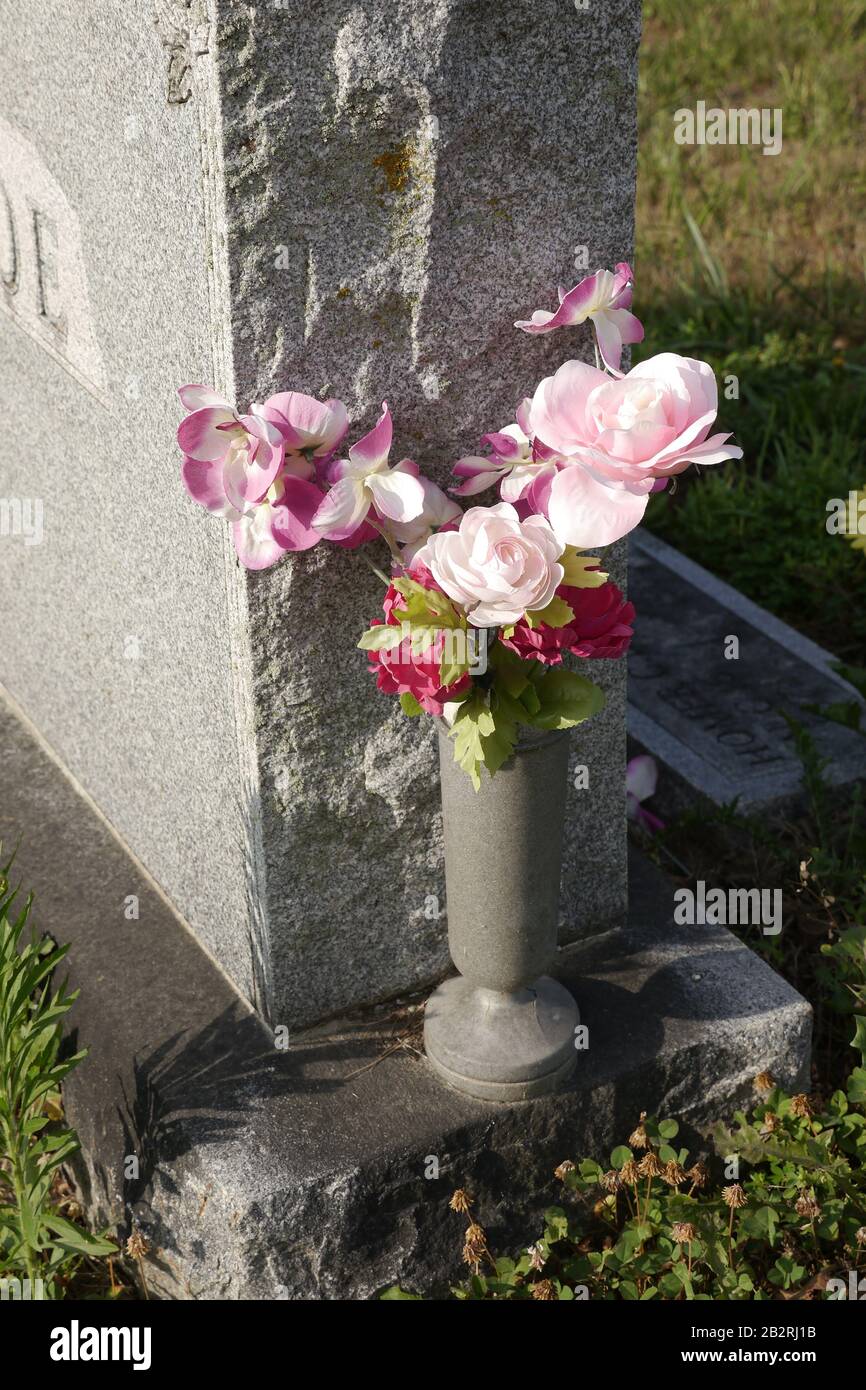 Closeup shot of the flowers in a stone vase near the cemetery headstone