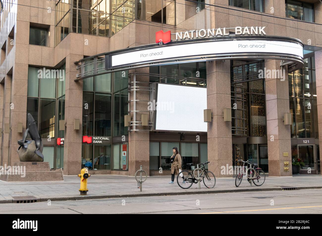 Front of a National Bank branch in downtown Toronto as a women walks by on a sunny afternoon. Stock Photo