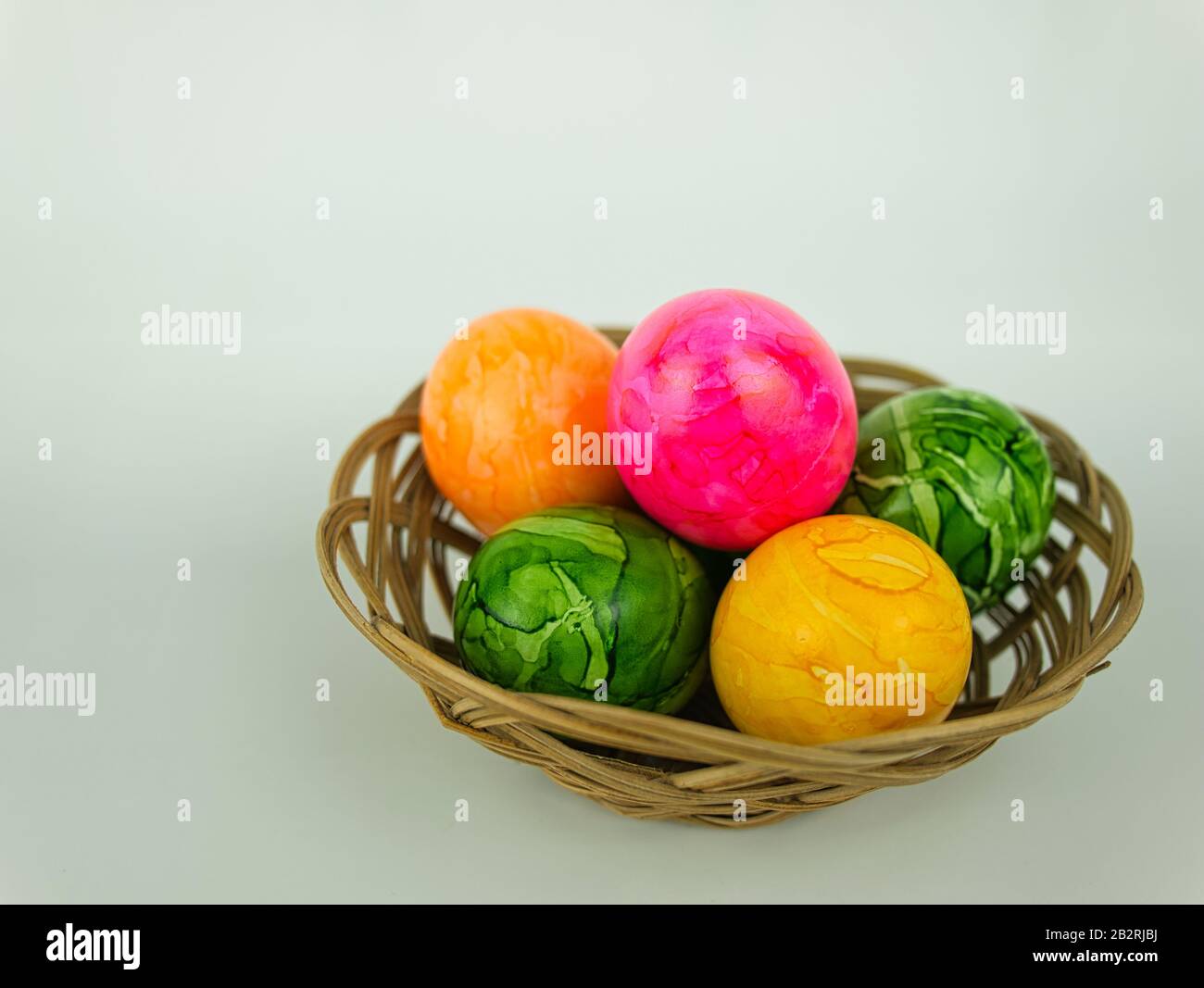 Five coloured Easter eggs in a small woven basket Stock Photo Alamy