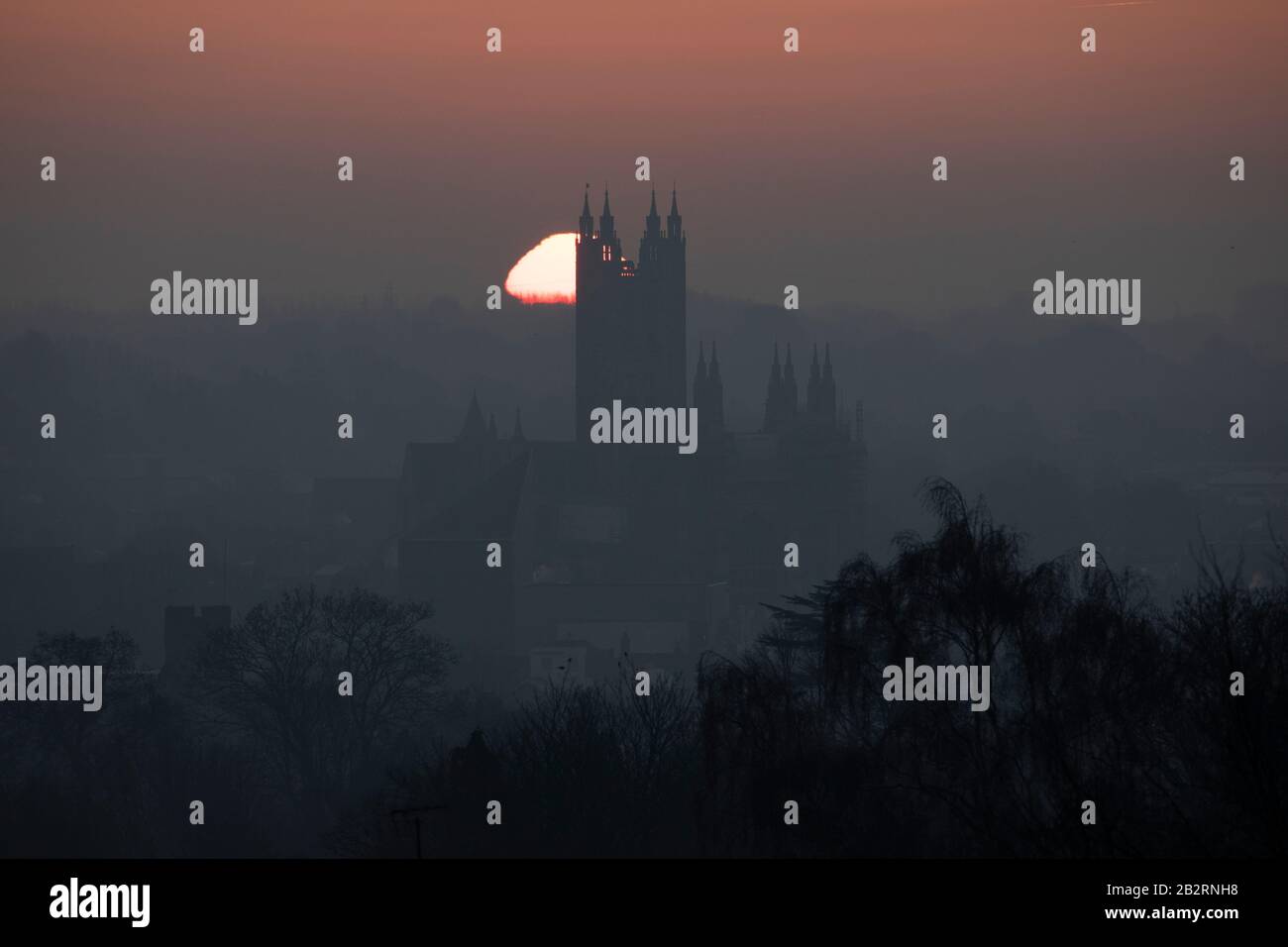 The sun rising behind Canterbury cathedral on a cold winter morning. Stock Photo