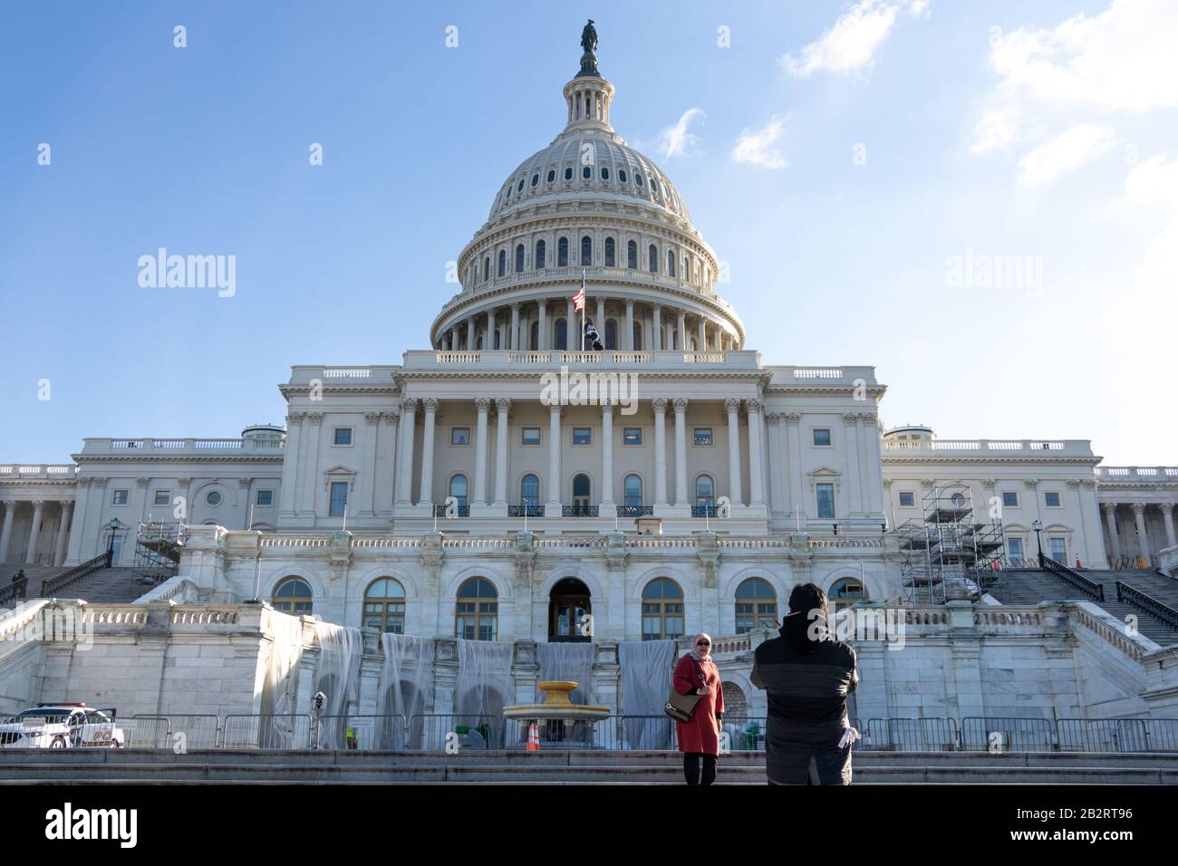 Couple take photos in-front steps to the US Capitol Building, west side on sunny day. Stock Photo