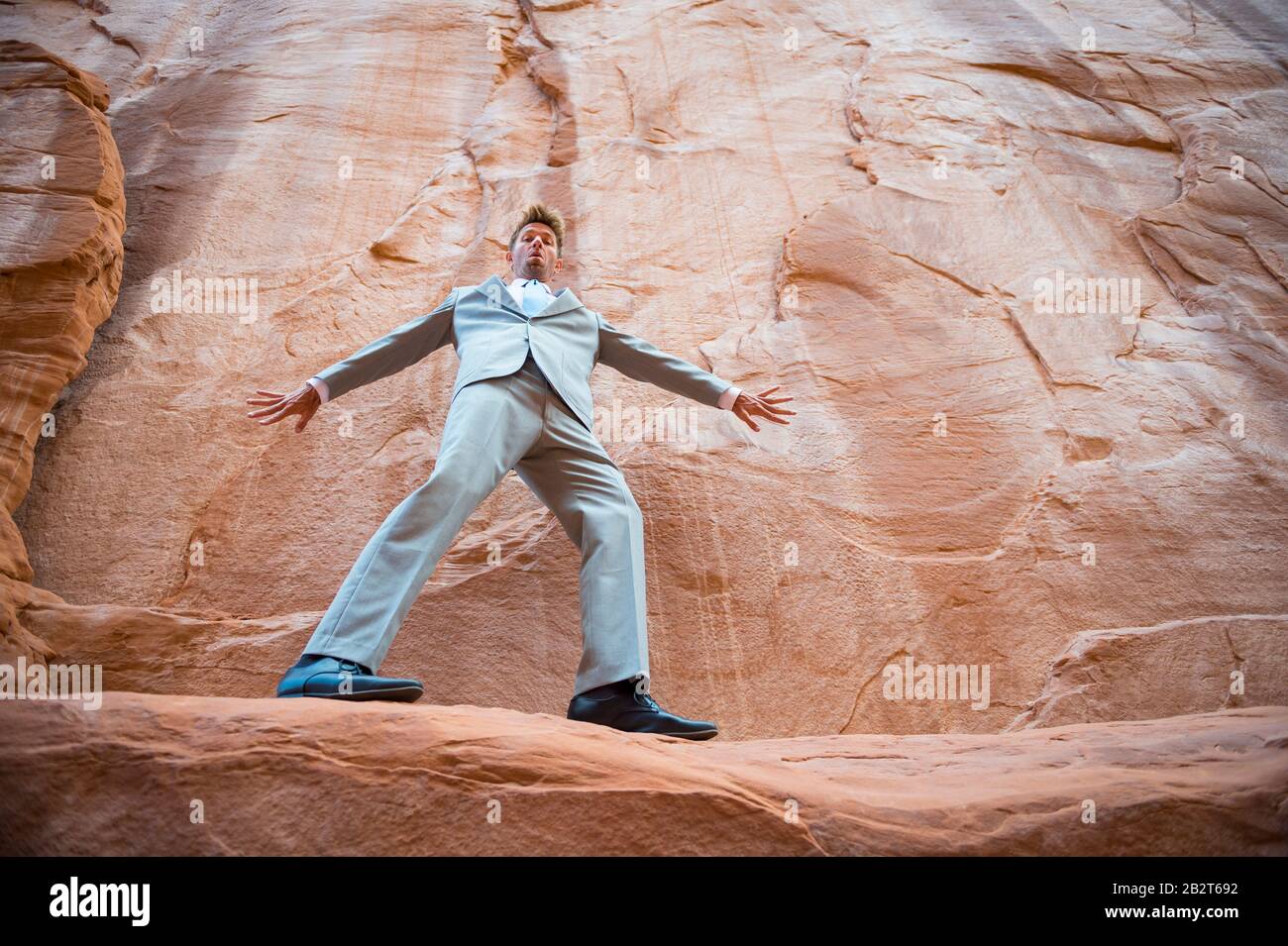 Nervous businessman balancing on a narrow ledge in a red rock canyon Stock Photo