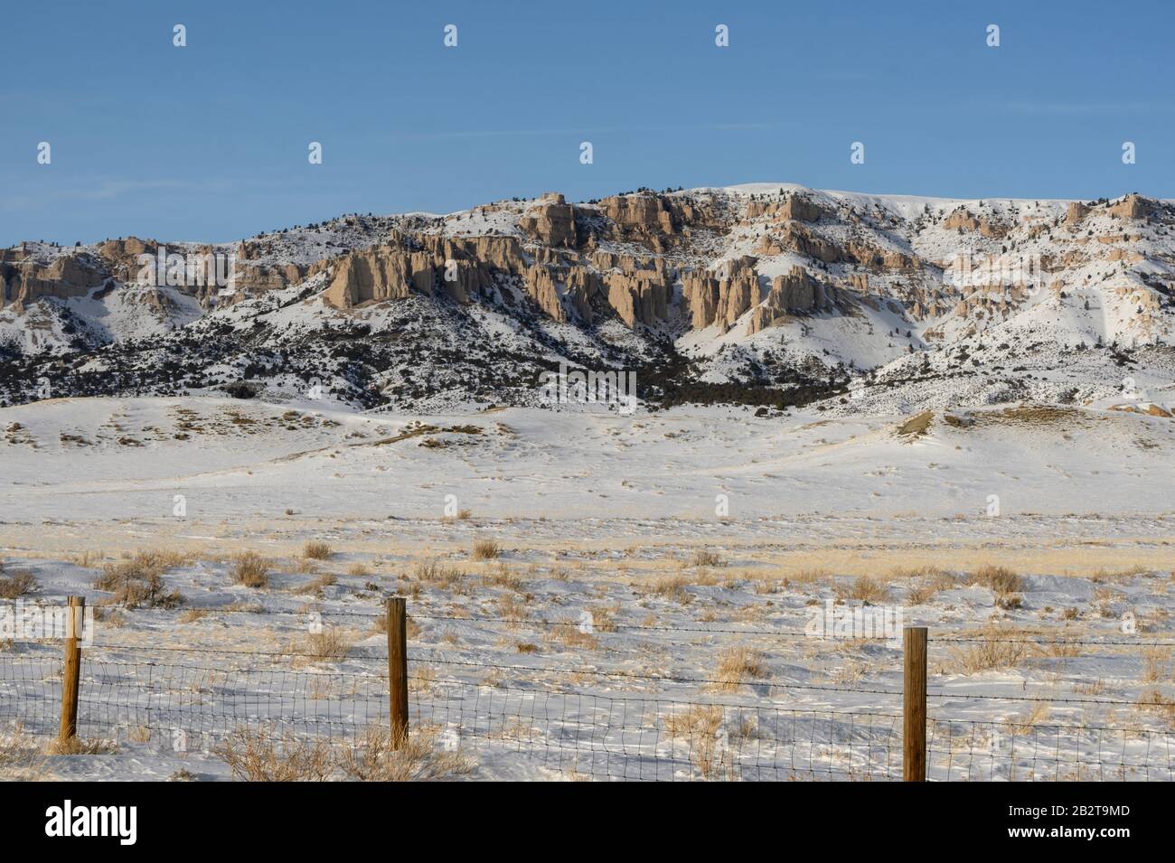 Wyoming landscape scene of a snowy hillside and rock outcropping in a rural area. Stock Photo