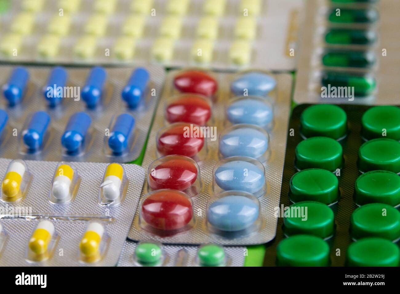 Pills of different colours lay on blue background. Colorful antibacterials pills, capsules of medicine Stock Photo
