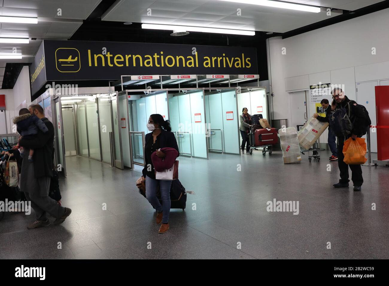 Travellers wearing face masks arrive gatwick airport hires stock