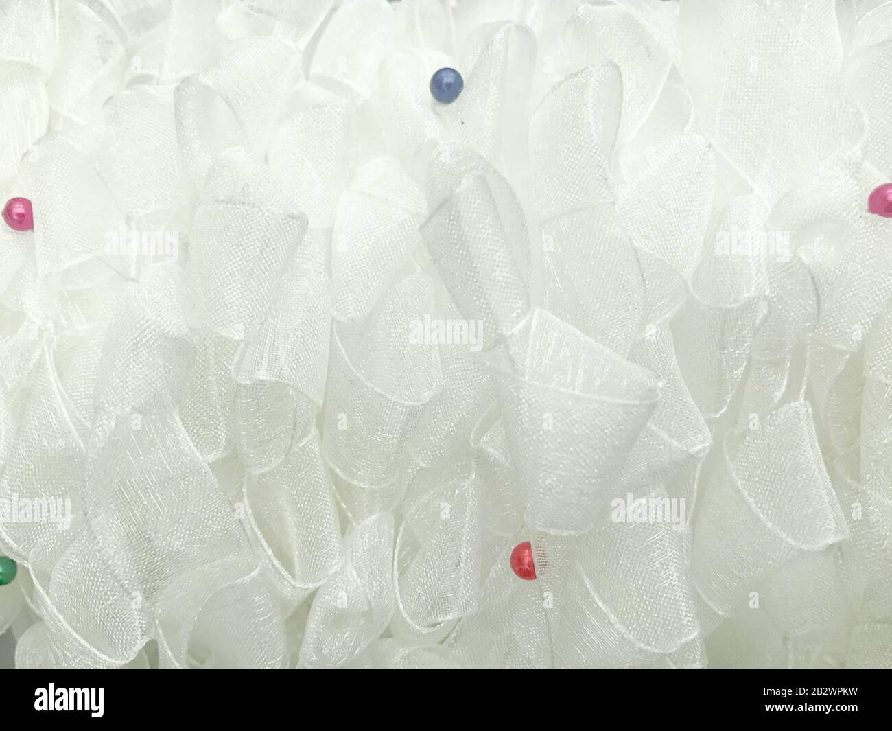 White handmade airy chiffon tulle ribbons curled soft organza fabric with color beads. Texture background Stock Photo