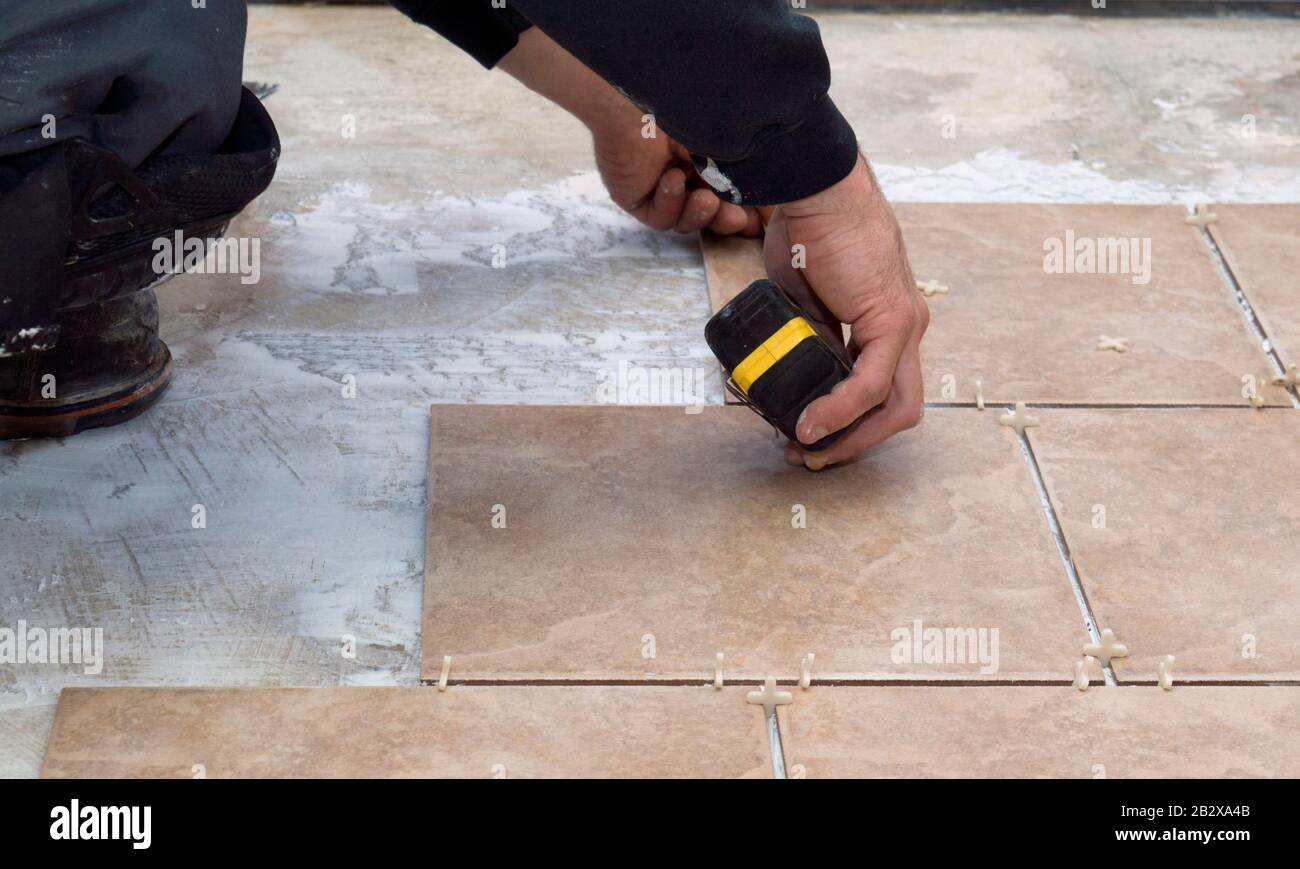 A Contractor Installing And Measuring Ceramic Tiles And Adding