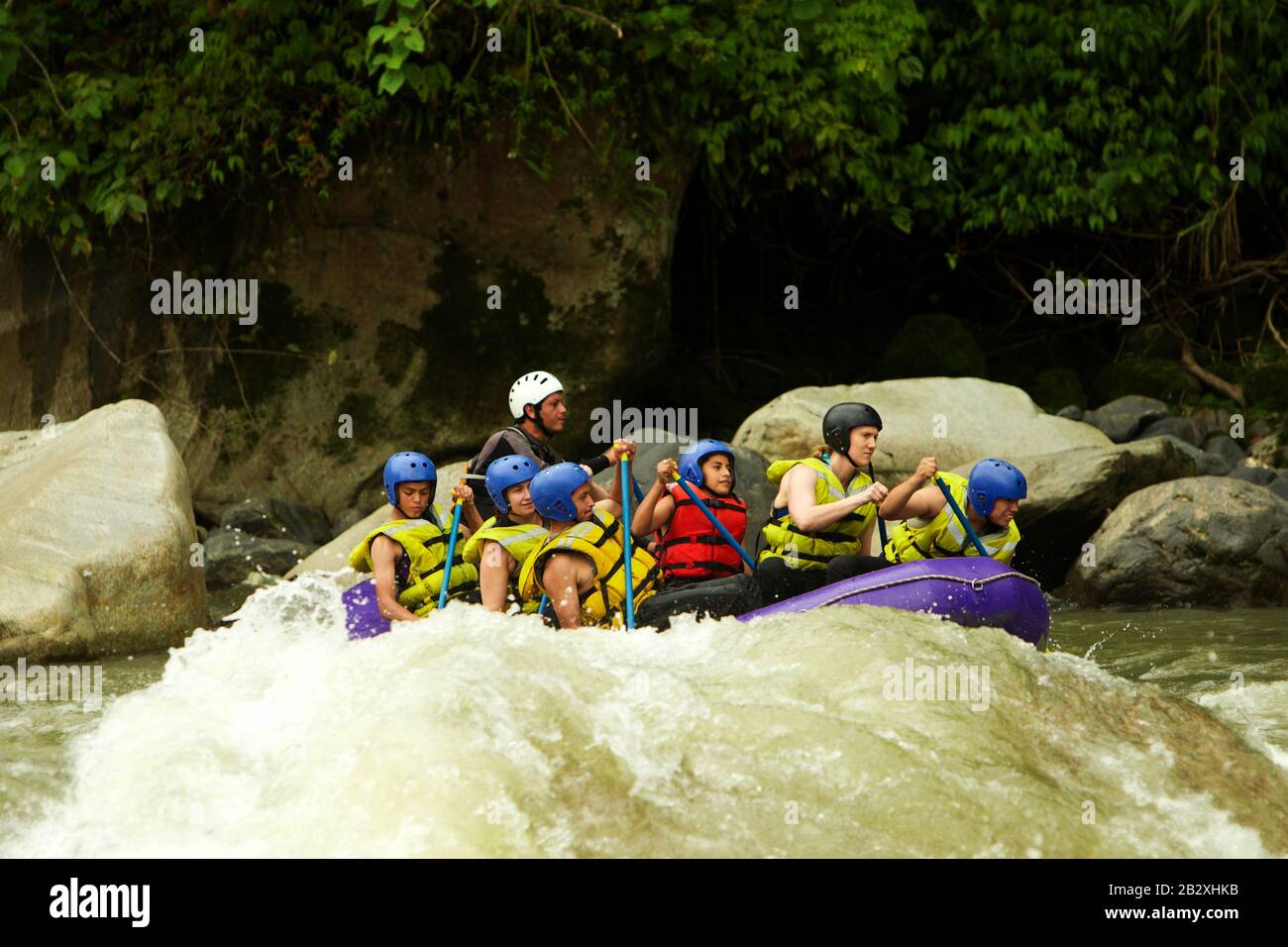 Community Of Mixed Visitor Men And Women With Guided By Specialist Pilot On Whitewater Creek Rafting In Ecuador Stock Photo