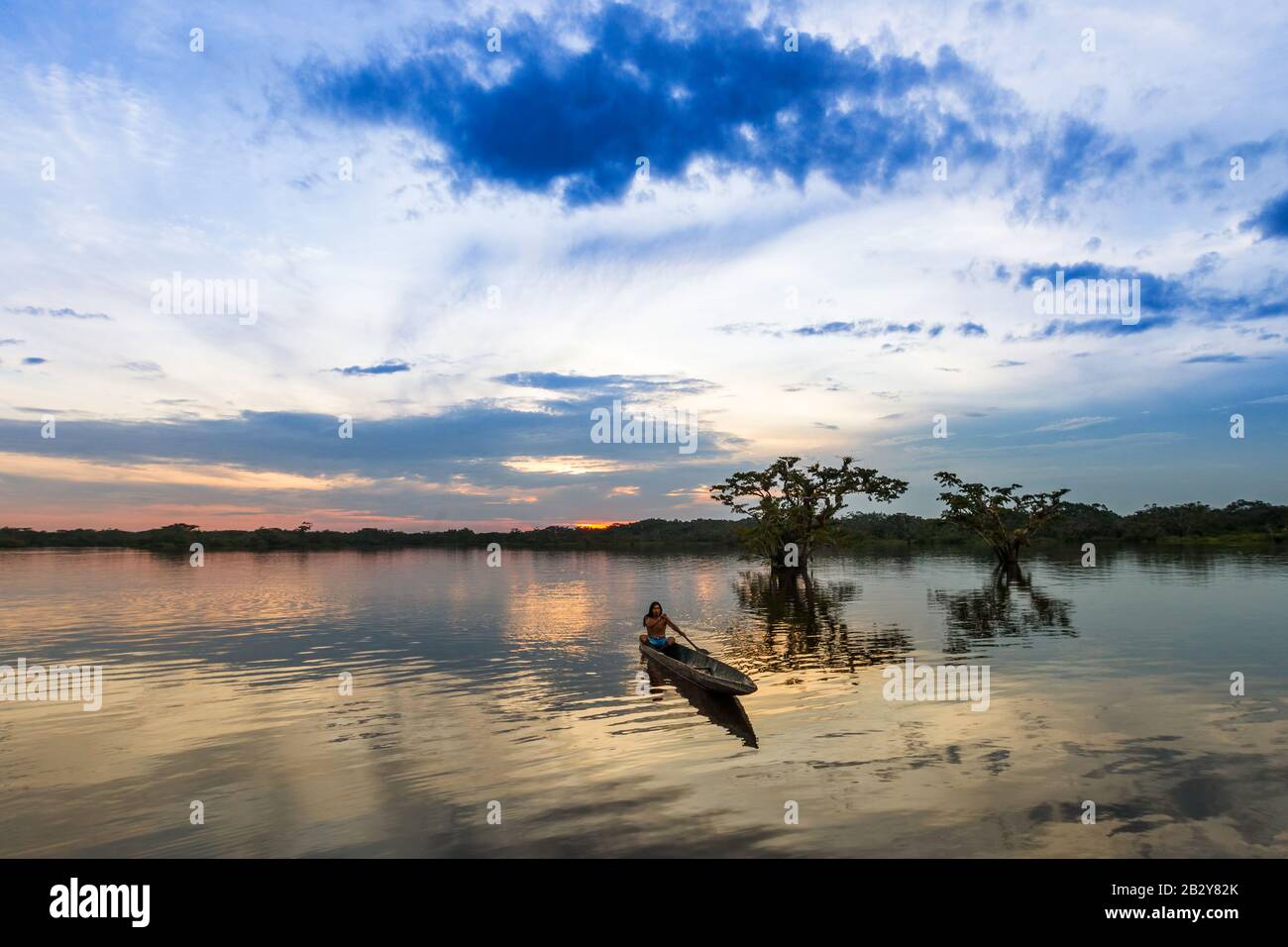 Cuyabeno National Park Sucumbios Ecuador Indigenous Adult Man With Wooden Canoe Against Blue Sunset Sky Stock Photo