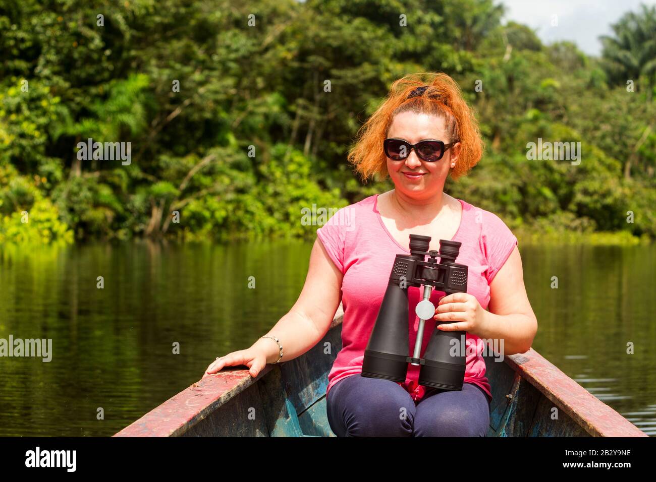 Mountaineer Woman With High Power Binoculars In Amazonian Forestry Against Dense Vegetation Stock Photo