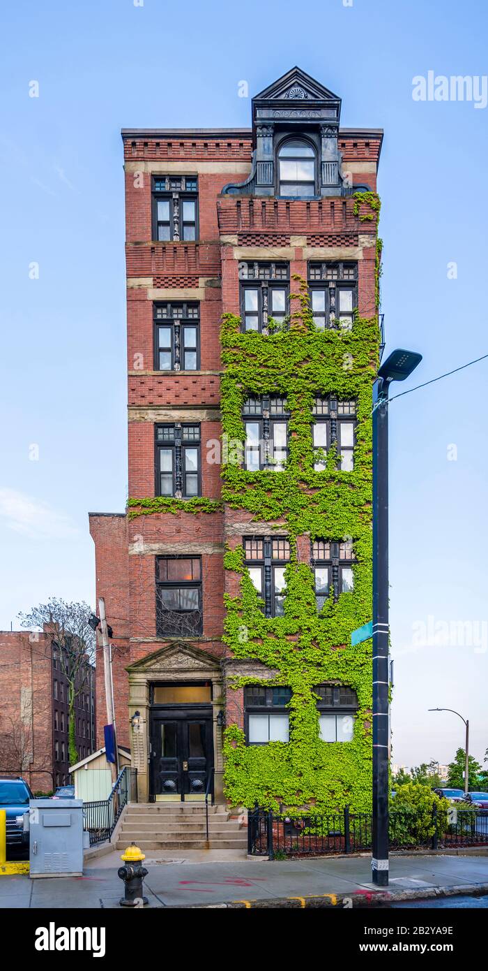 A narrow multistory red brick apartment building on a street in Boston