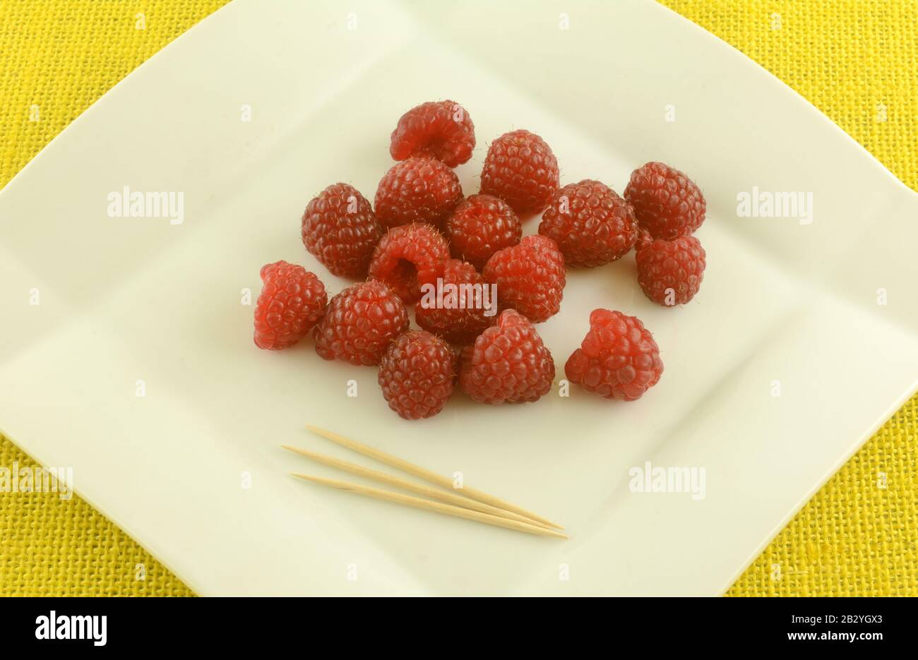 Fresh raw red raspberries on white snack plate with toothpicks Stock Photo