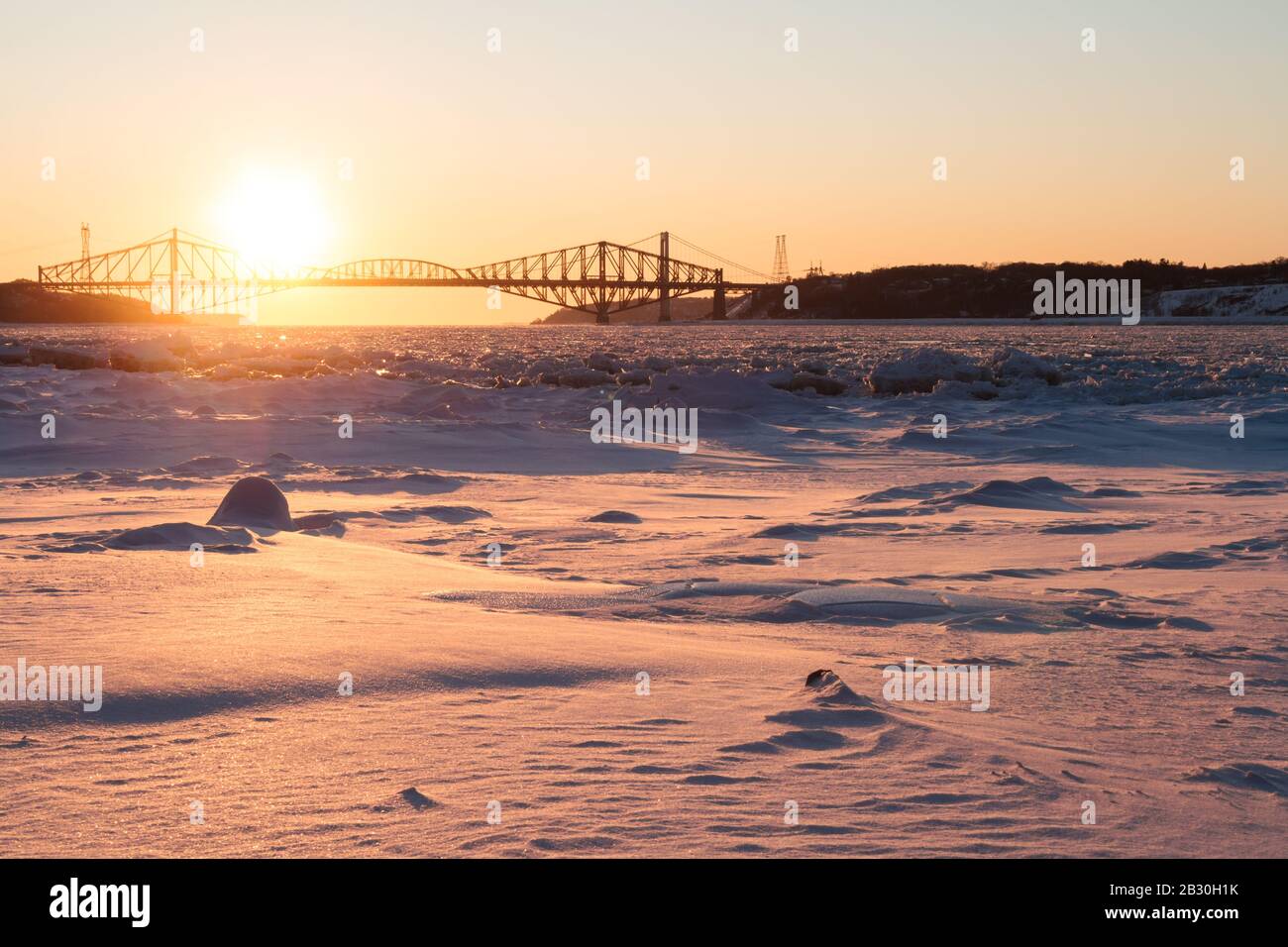 Old Quebec bridge in winter at sunset on beautiful day with clear sky. Snow and ice covering Saint-Lawrence River. Lévis, Qc. Canada Stock Photo