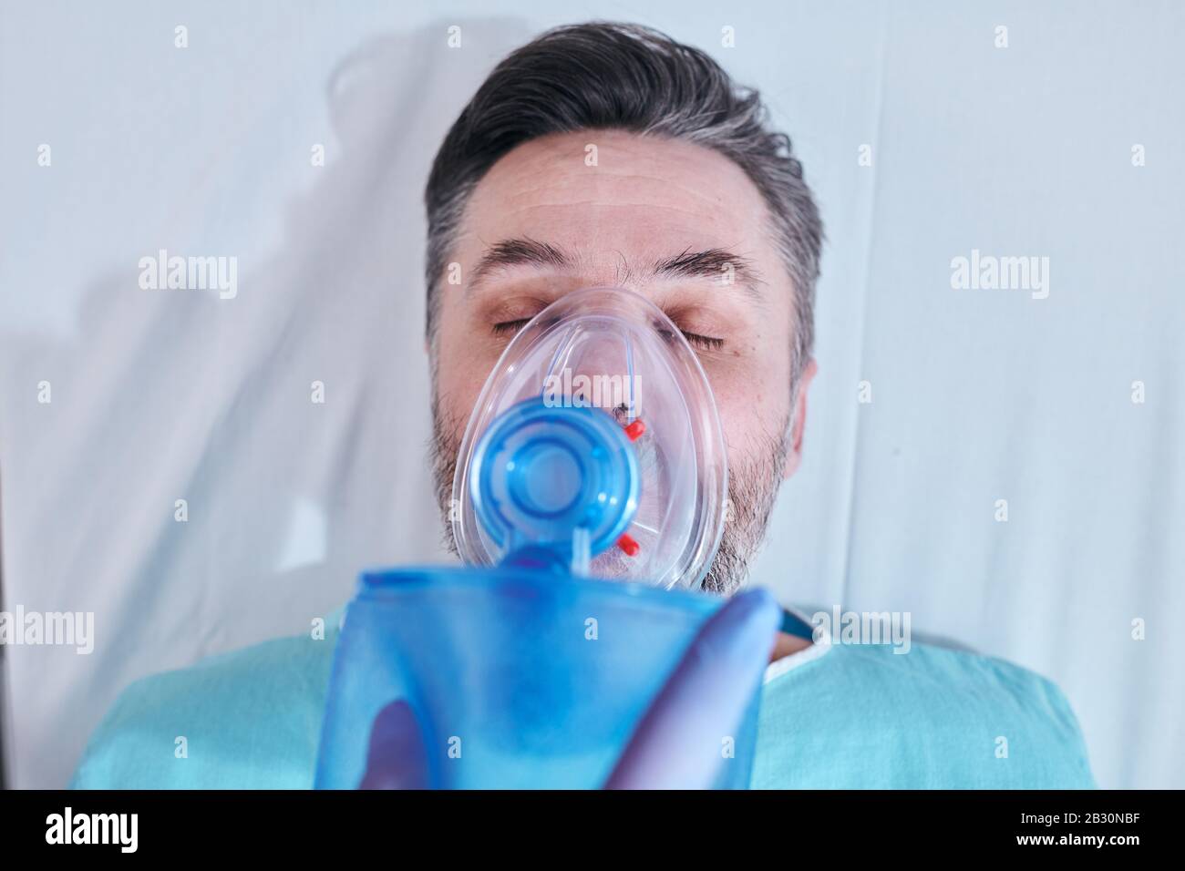 Above view of mature patient in serious condition keeping eyes closed while inhaling oxygen