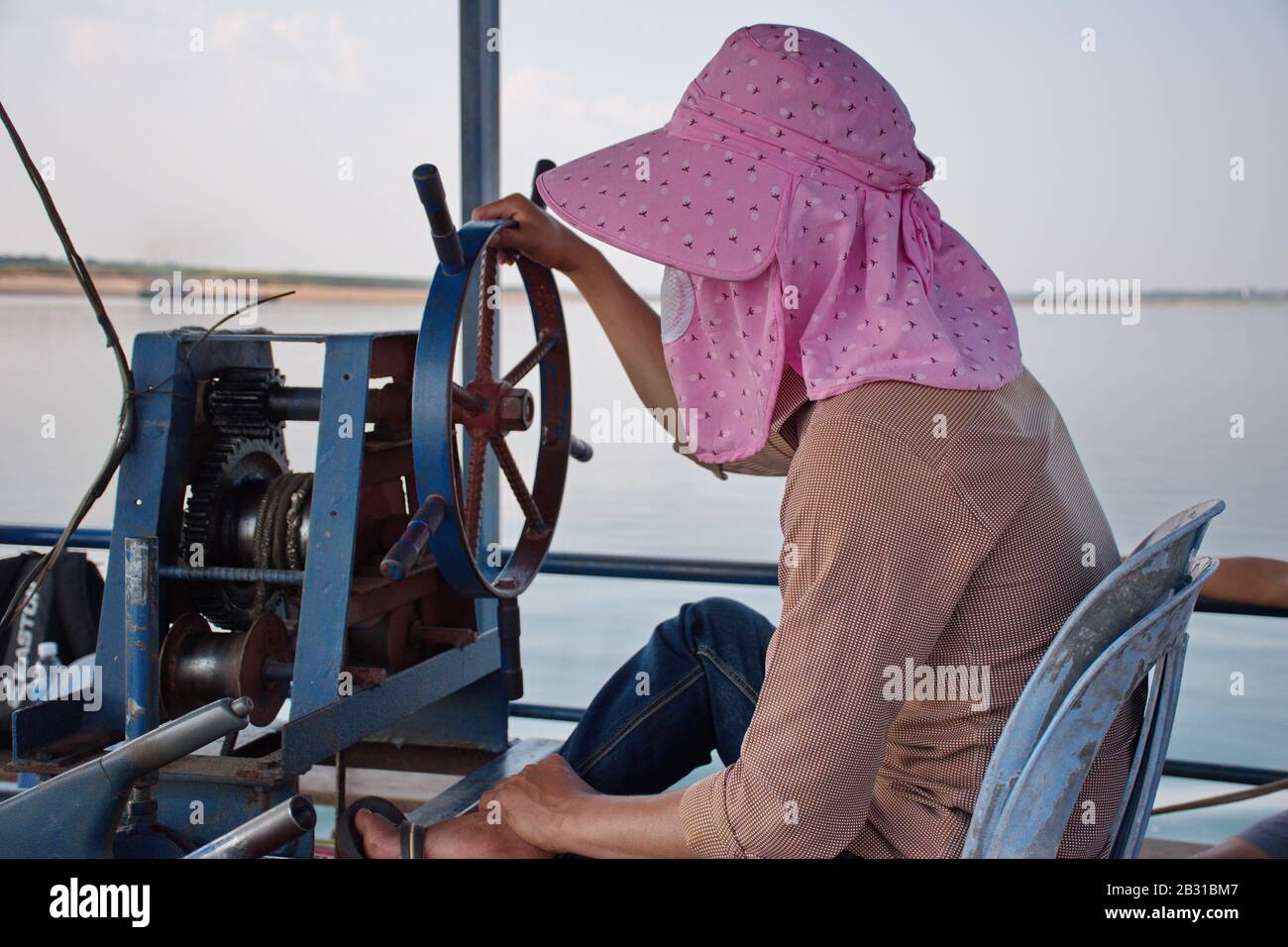 Portrait of Cambodian man driving boat with pink hat Stock Photo - Alamy