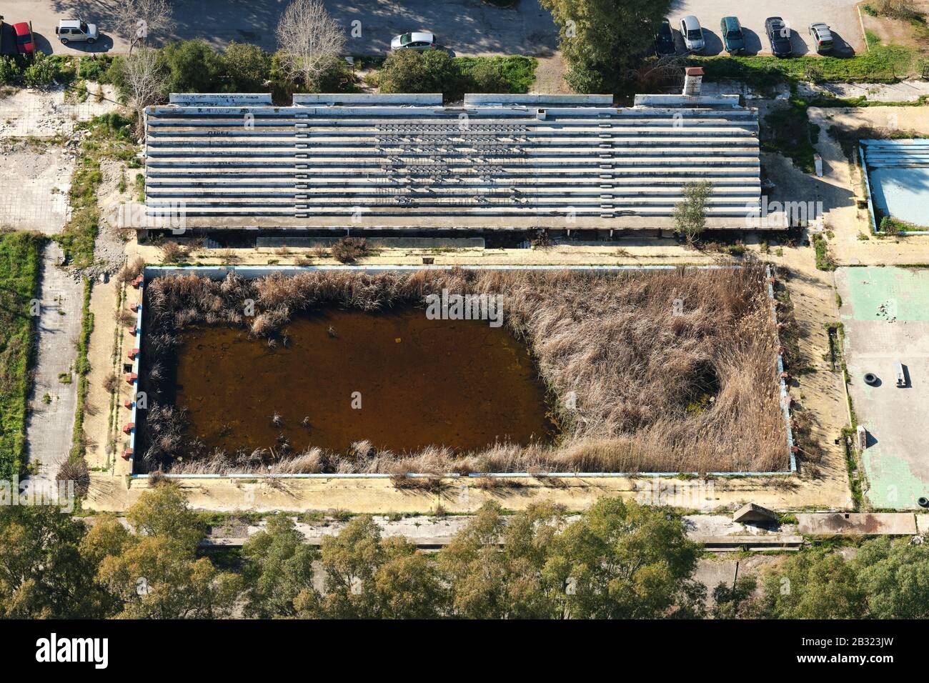 AERIAL VIEW. Abandoned olympic-size swimming pool reclaimed by vegetation. Patras, West Greece, Peloponnese Peninsula, Greece. Stock Photo