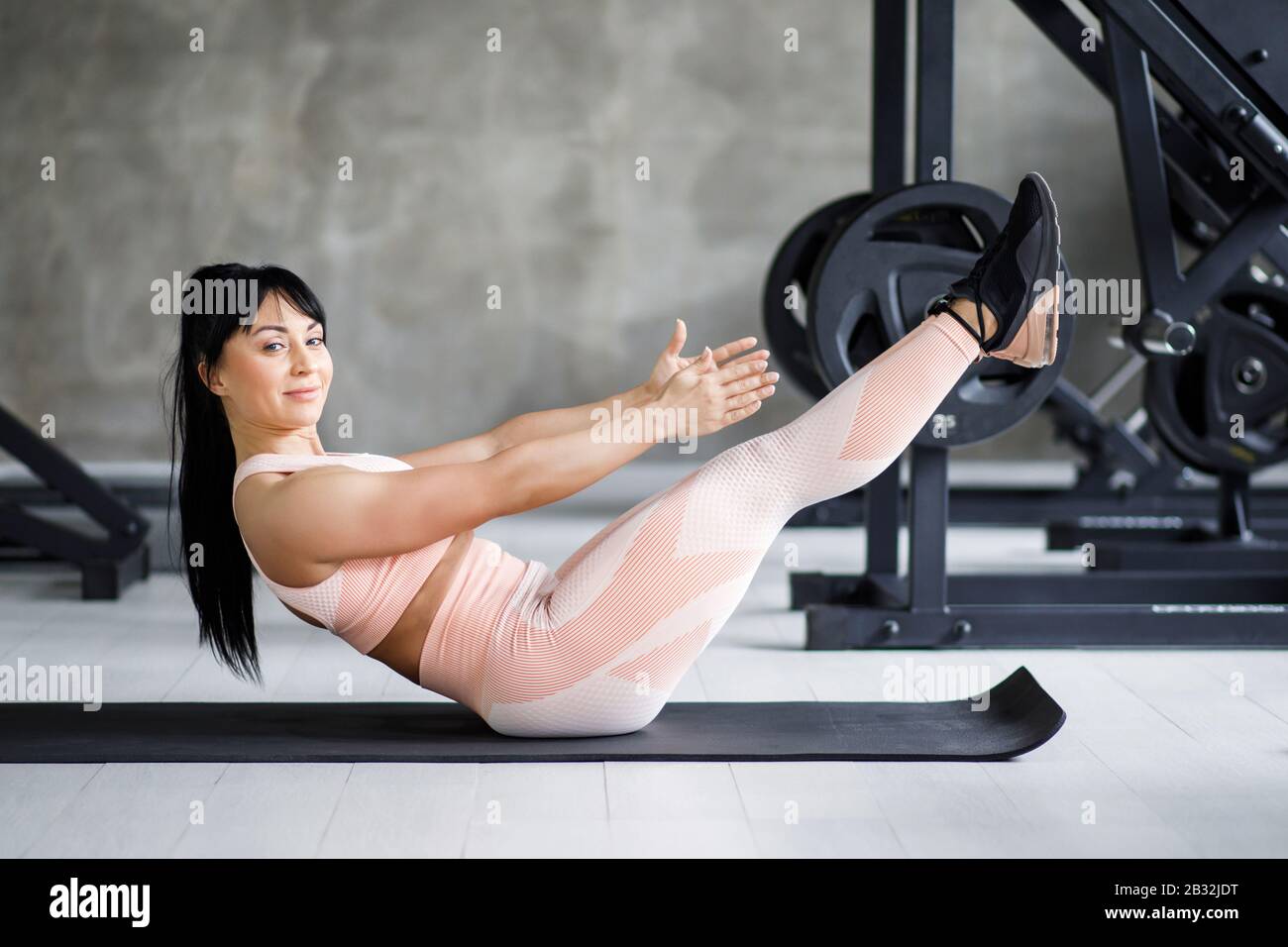 Young pretty woman, middle-aged, well-built physique, performs exercises on the press. Active lifestyle Stock Photo