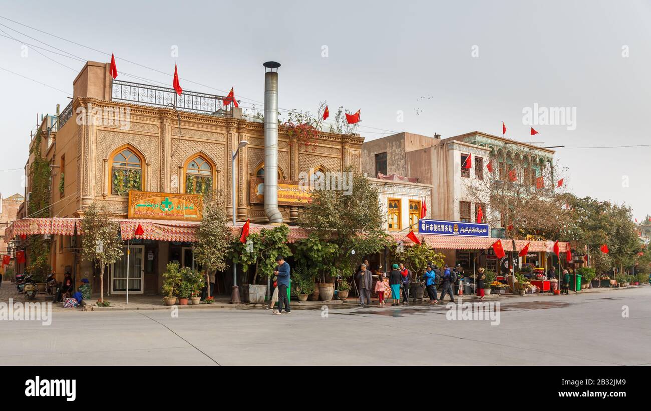 Street in Kashgar Old Town: Houses of the Uyghur minority with an integrated police station. Chinese flags all over the building. Stock Photo