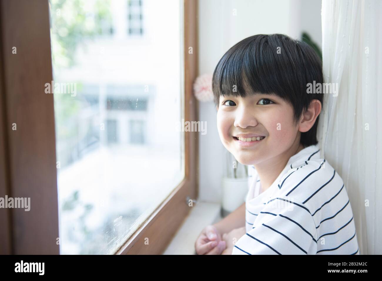 Portrait of happy asian school child boy smile in first day of back to school,Intelligent smart boy standing face to window in classroom Stock Photo