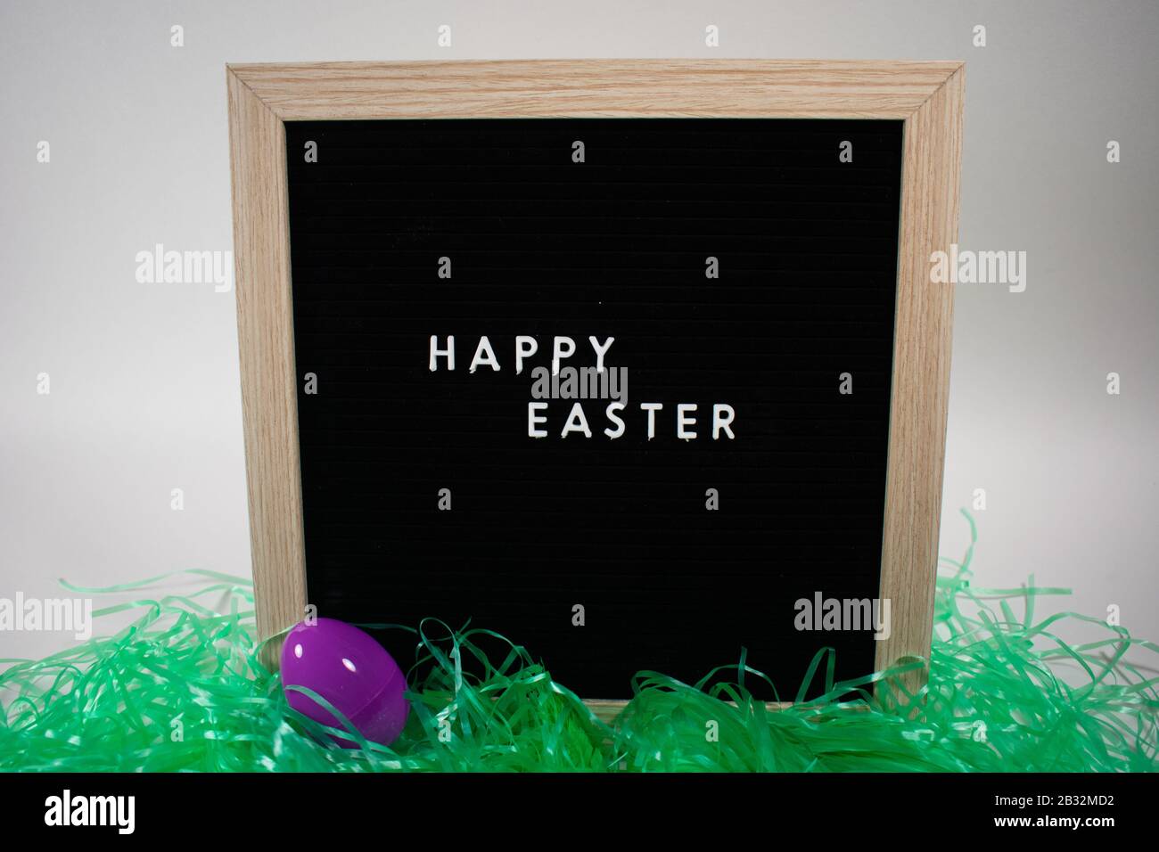 A Black Happy Easter Sign With White Letters, Easter Grass, and Easter Eggs Stock Photo