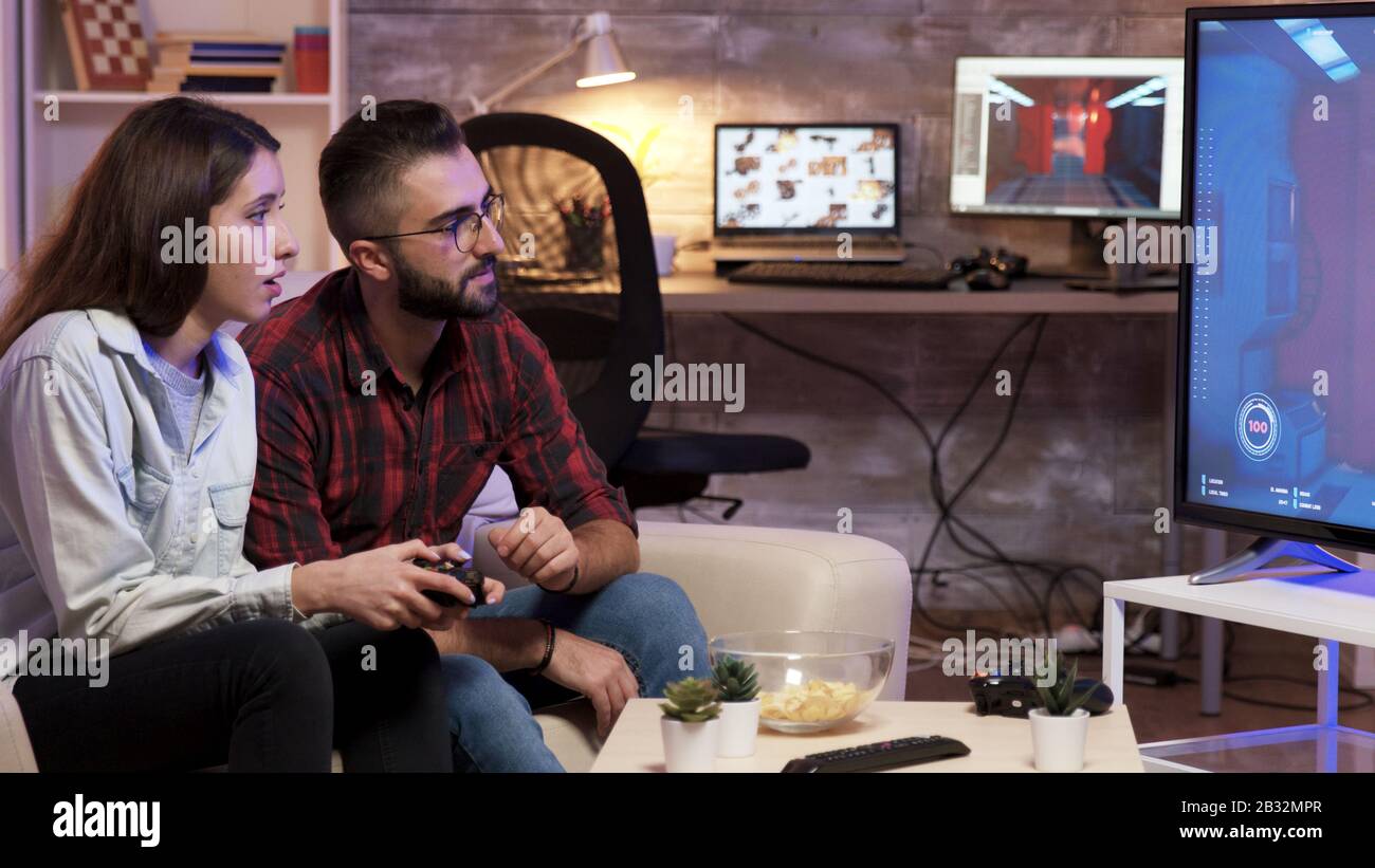 Man sitting on couch learning his girlfriend to play video games on television. Stock Photo