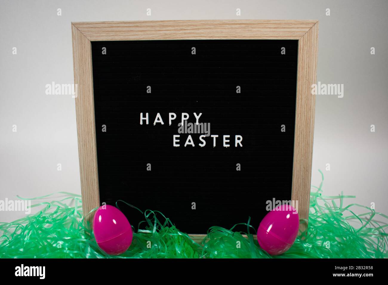 A Black Happy Easter Sign With White Letters Easter Grass and Easter
