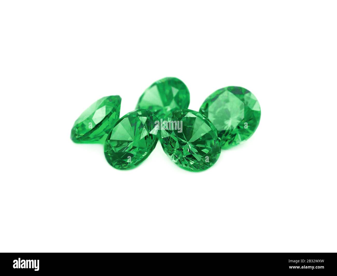 Five faceted emeralds on a white background. Stock Photo