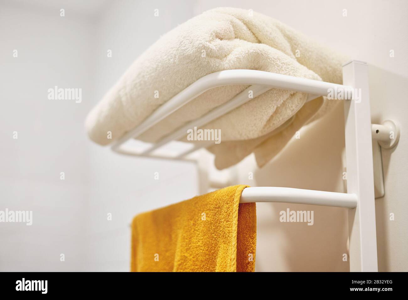 Electric towel rail for drying wet towels. White pipes. Stock Photo