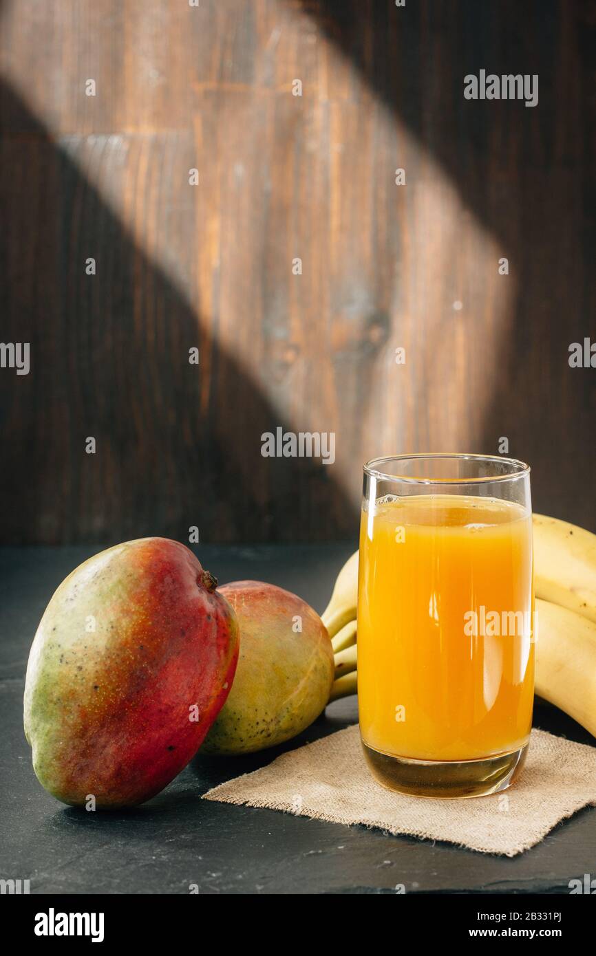 Glass filled by mango and banana juice over black surface Stock Photo