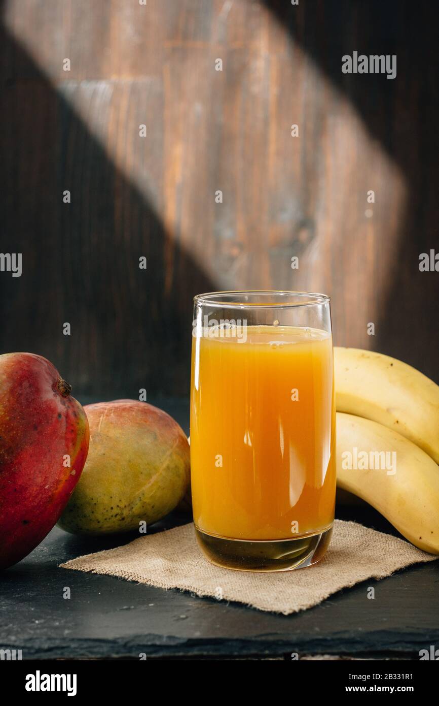 Glass filled by mango and banana juice over black surface Stock Photo
