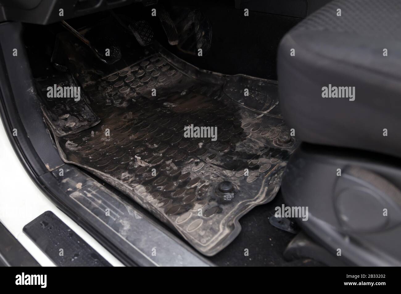 Dirty car floor mats of black rubber with gas pedals and brakes in